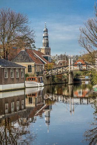 The dominant church tower of Hindeloopen with a classic bridge in the foreground