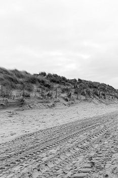 Strand en duinen met bandensporen in zwart-wit