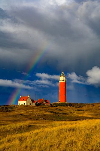 Texelse vuurtoren in de duinen met een regenboog tijdens een stormachtige aut