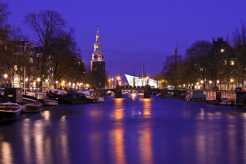 Stadsbeeld van Amsterdam met de Montelbaan toren bij avond in Nederland van Eye on You