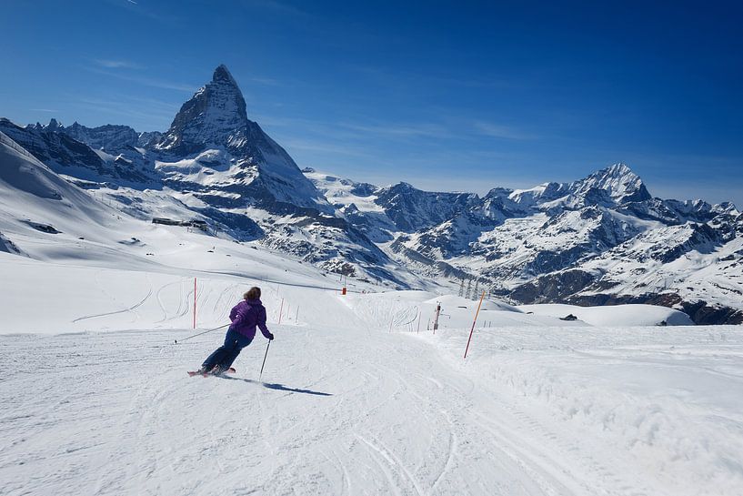 Weiblicher Skifahrer, der auf den Steigungen des Matterhorn Berges Ski fährt von iPics Photography