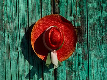 Rode strohoed hangt aan een poort van Matthias Stolt