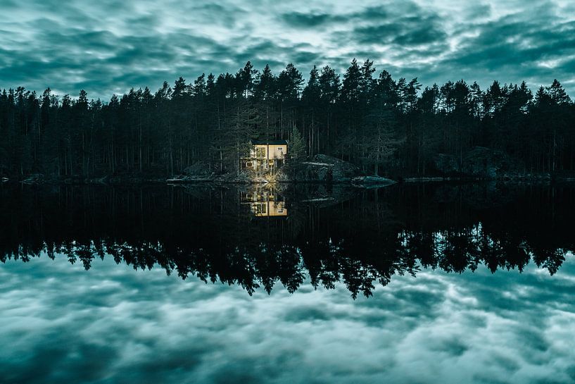 Oplichtende hut aan reflecterend meer met dramatische lucht van Joep van de Zandt