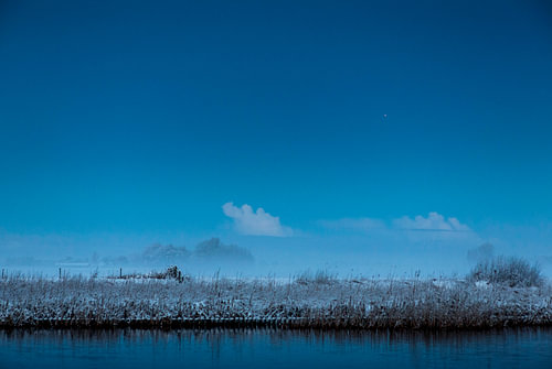 besneeuwde waterkant bij volle maan 