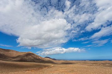 Droog en dor Lanzarote met een streepje oceaan aan de horizon.