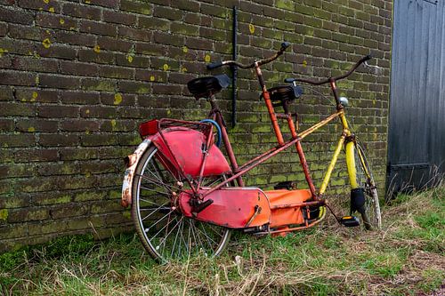 Oude tandem fiets tegen een muur