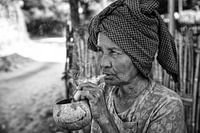 Old wrinkled woman smokes traditional cheroot cigar in front of her home in Baghan in Myanmar