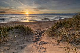Pad door de duinen leidt naar het strand waar het genieten is van de ondergaande zon. van Bram Lubbers