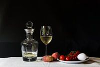 Still life with wine carafe, wild peach, tomatoes and eggs.