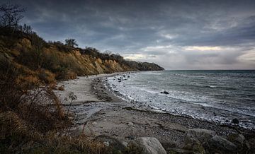 Steilküste mit Strand, Steinen und Wellen unter dunklem Wolkenhimmel an der Ostsee in Mecklenburg-Vo von Maren Winter