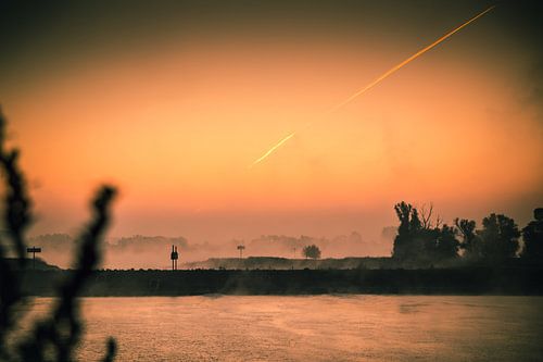 Zonsopkomst naast de Waalbrug bij Nijmegen met de mist die langzaam verdreven wordt door de opkomend