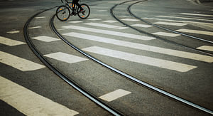 Kurvige Schienen & Zebrastreifen – Radfahrer am Bildrand