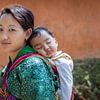 Jonge bhutanese vrouw mat baby op rug in Wangdi Bhutan. Wout Kok One2expose van Wout Kok