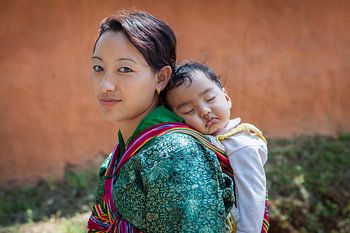 Young bhutanese woman mats baby on back in Wangdi Bhutan. Wout Kok One2expose