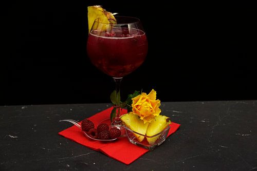 Gin cocktail met frambozen en ananas.