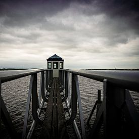 small lighthouse at the lauwersmeer during a rainstorm by nick ringelberg