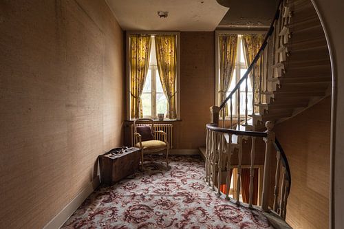 A suitcase with a chair in the corridor of an abandoned mansion.
