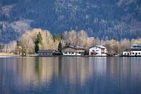 Reflections of cottages bordering a mountain lake.