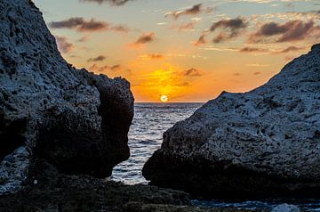 Zonsondergang bij tussen de rotsen bij Blue Bay, Curacao van Joke Van Eeghem