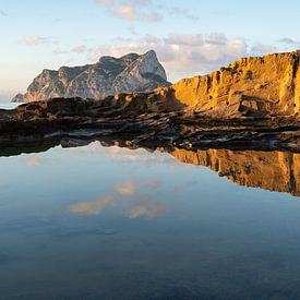 Reflection of the rocky coast in the calm sea by Adriana Mueller