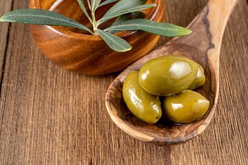 Green olives on a wooden spoon