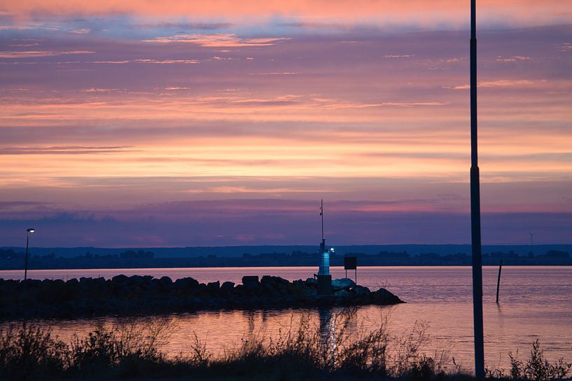 Lighthouse in the harbour at sunset by Martin Köbsch