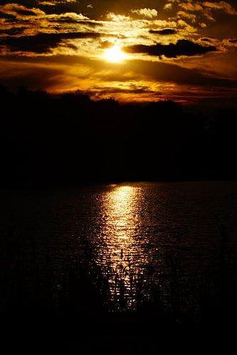 Zonsondergang met reflectie in het water en bewolkte lucht