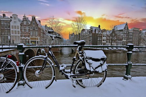 Stadsgezicht van besneeuwd Amsterdam bij zonsondergang