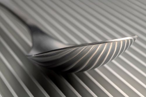 Abstracte artistieke foto van couvert, zijnde een lepel op een parallelle rasterstructuur