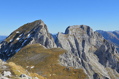 Sommets alpins et sentier de randonnée sous un ciel d'automne d'un bleu éclatant