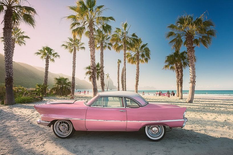 Rosa 1960er Chevrolet an einem sonnigen Strand mit Palmen von Patricia Hofmeester