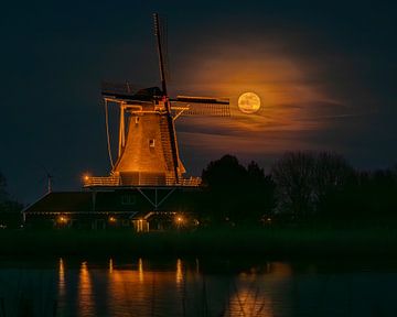 La pleine lune est filmée à travers la voile du moulin Leonide à Anna Paulowna. sur Bram Lubbers