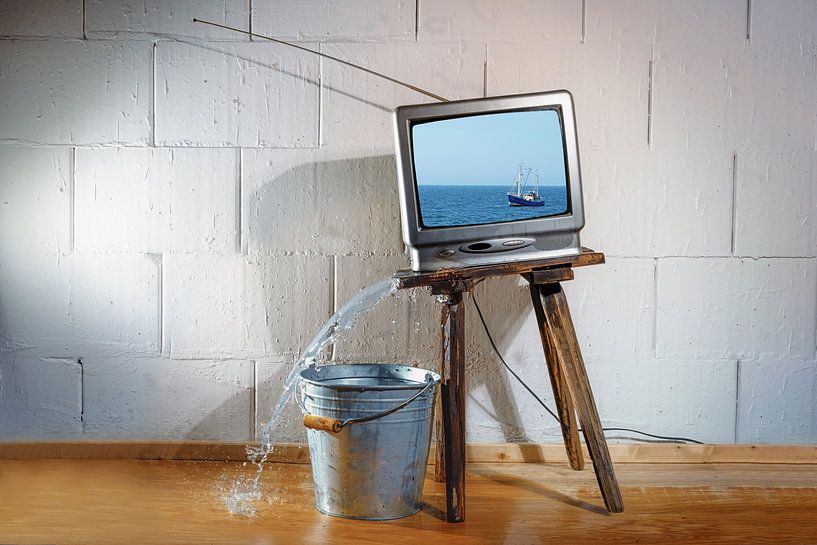 Un vieux téléviseur vintage posé sur un tabouret en bois incliné montre un film sur un bateau.  par Maren Winter