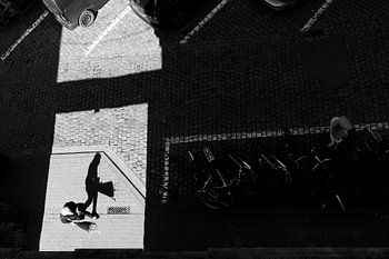 Schaduwspel in de stad - Minimalistische zwart-wit straatfoto van een man met een boeket bloemen