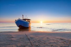 Boat on the beach in front of the rising sun by Tilo Grellmann