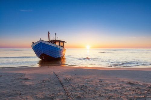 Boat on the beach in front of the rising sun