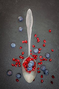 Silver spoon with blueberries and pomegranate seeds