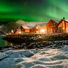 Aurore boréale au-dessus des cabanes de pêcheurs rouges dans la neige à Lofoten, Norvège sur Marion Stoffels