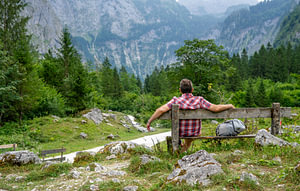 Älterer Mann macht eine Pause auf einer Bank in den bayerischen Alpen