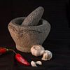 Still life of a      Still life of an Indonesian mortar with red peppers and garlic against a black by Birgitte Bergman