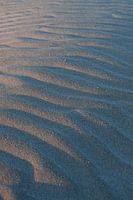 Wellenförmiger Sand am Sandstrand - Nahaufnahme von kleinen Hügeln in den Dünen bei Sonnenaufgang