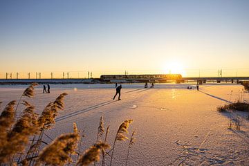 Een Sprinter rijdt over de by-pass bij Kampen met schaatsers op de bevroren hoogwatergeul van Stefan Verkerk fotografie