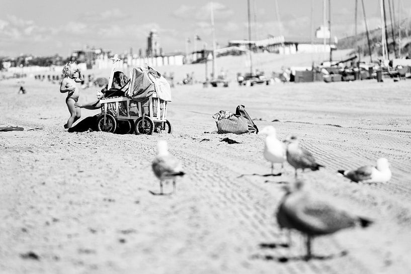 Eine Mutter am Strand von Katwijk aan Zee reibt ihr Kind mit Sonnenschutzmitteln; im Vordergrund lau von Evert Jan Luchies