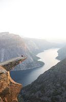 Een persoon zit op de Trolltunga in Noorwegen bij zonsondergang