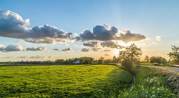 Typisch Nederlands polderlandschap met prachtige wolken en ondergaande zon