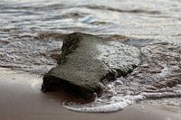 Water langs steen op het strand