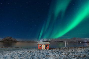 Rode houten hut in de sneeuw met aurora borealis