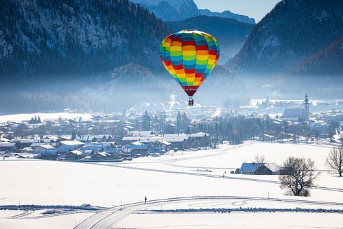 Heteluchtballonnen sieren de lucht boven een besneeuwd Inzell in Duitsland