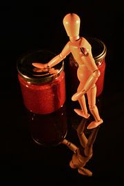 Canned fruit with wooden doll and black background by Hans-Jürgen Janda