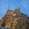 Das Castillo de Santa Bárbara in Alicante auf einem felsigen Berg unter einem klaren blauen Himmel. von LuCreator
